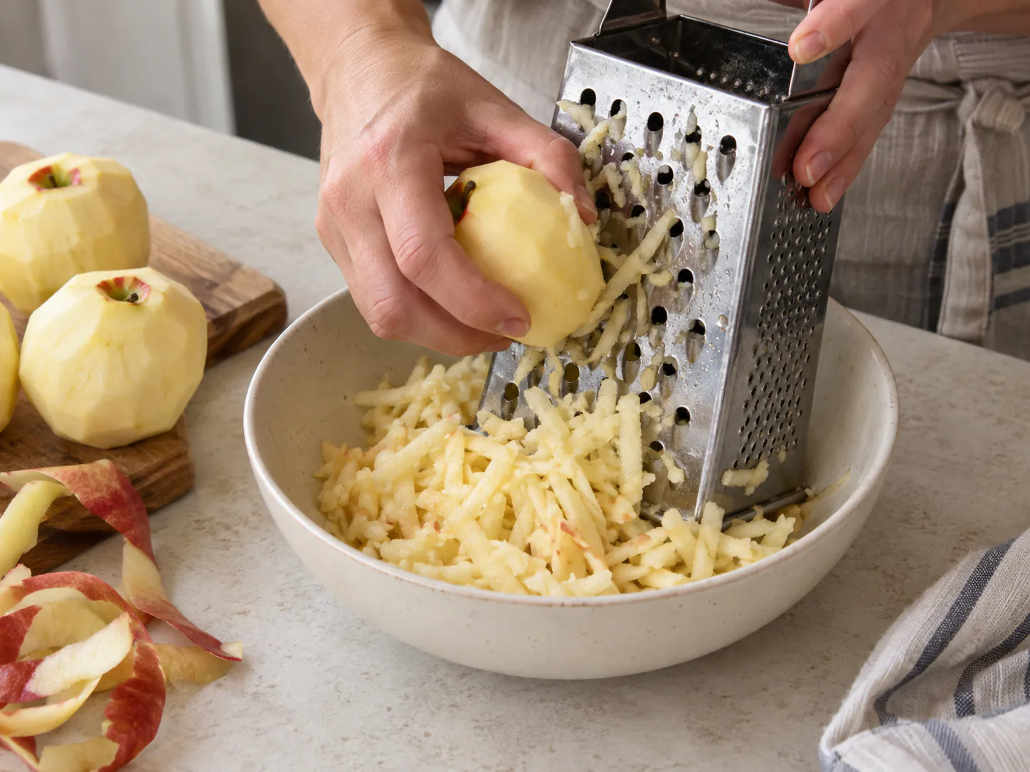 Peeled apples grated into coarse shreds in a ceramic bowl