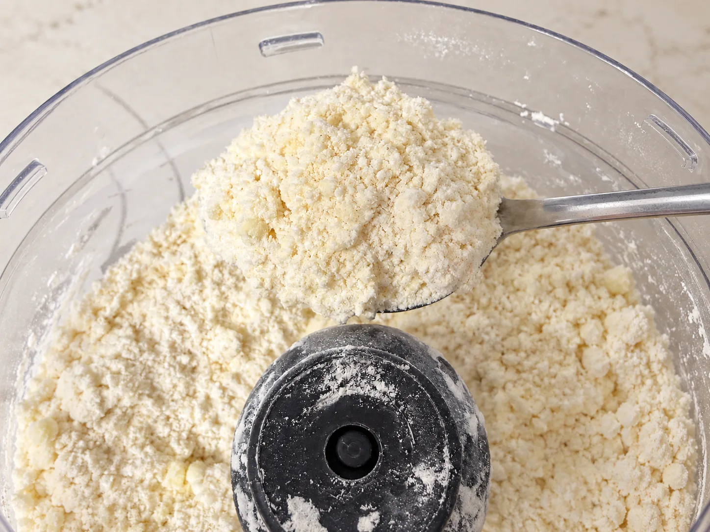 Fine butter and flour crumbs on a spoon in the food processor