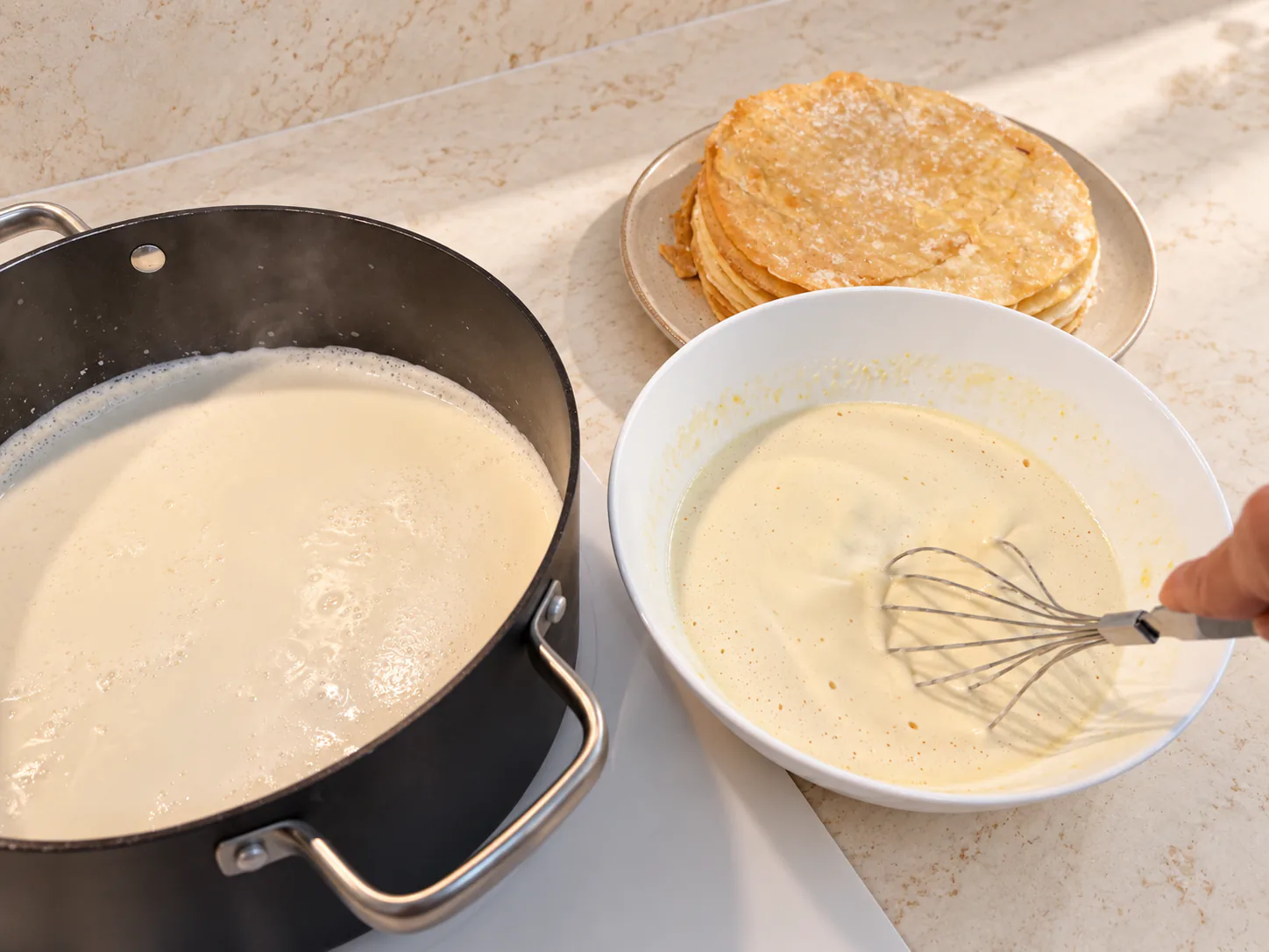 Egg mixture after adding hot milk, beside the saucepan