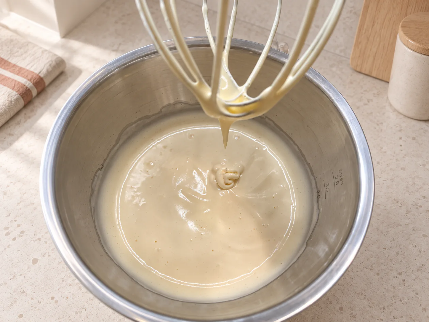 Pale whipped eggs falling from the whisk in a ribbon