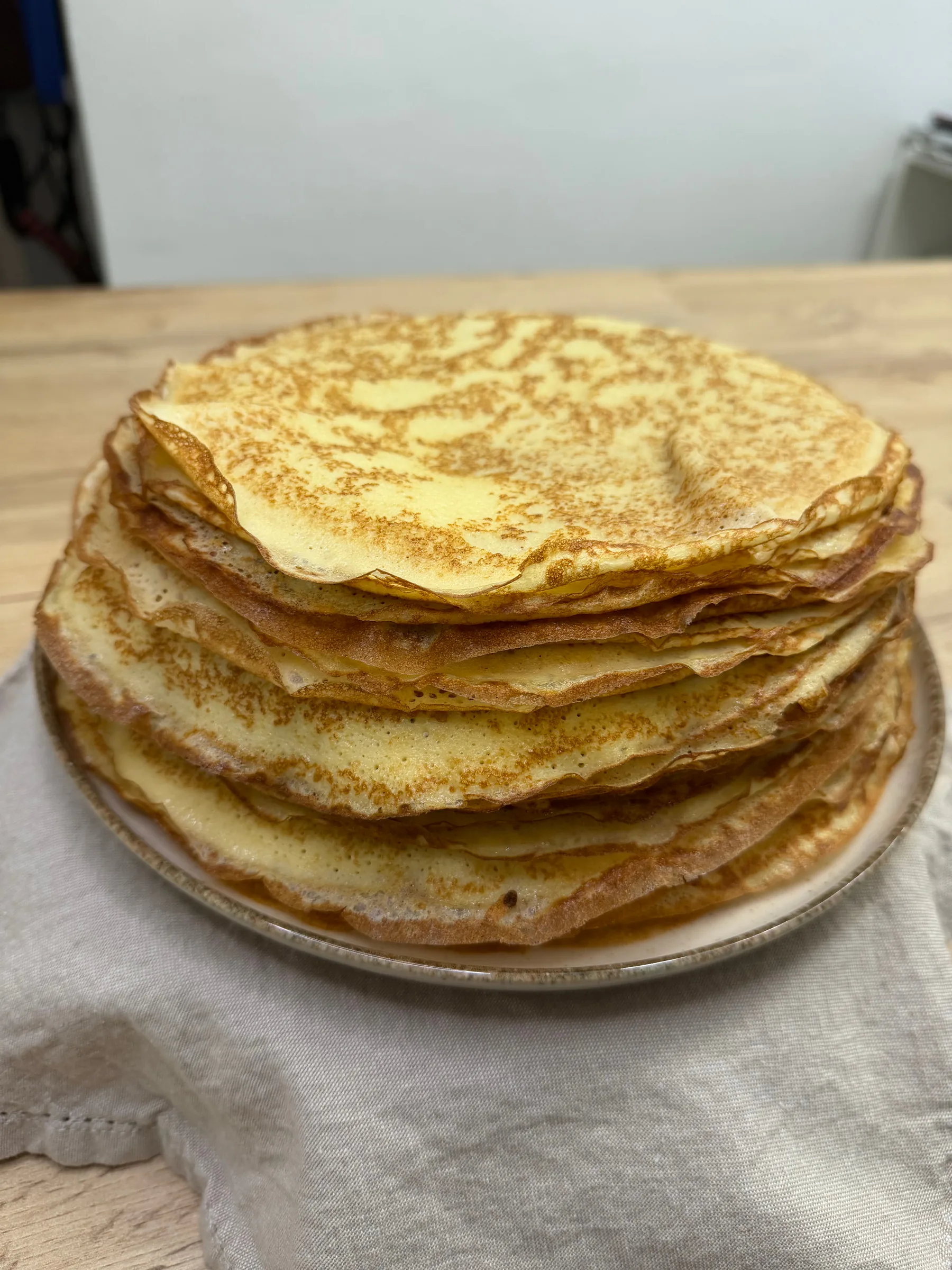 A tall stack of golden gluten-free crepes on a plate