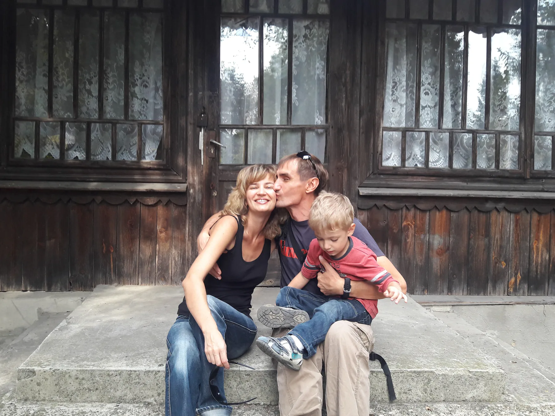 Our family with young Ivan on the steps of a wooden house.